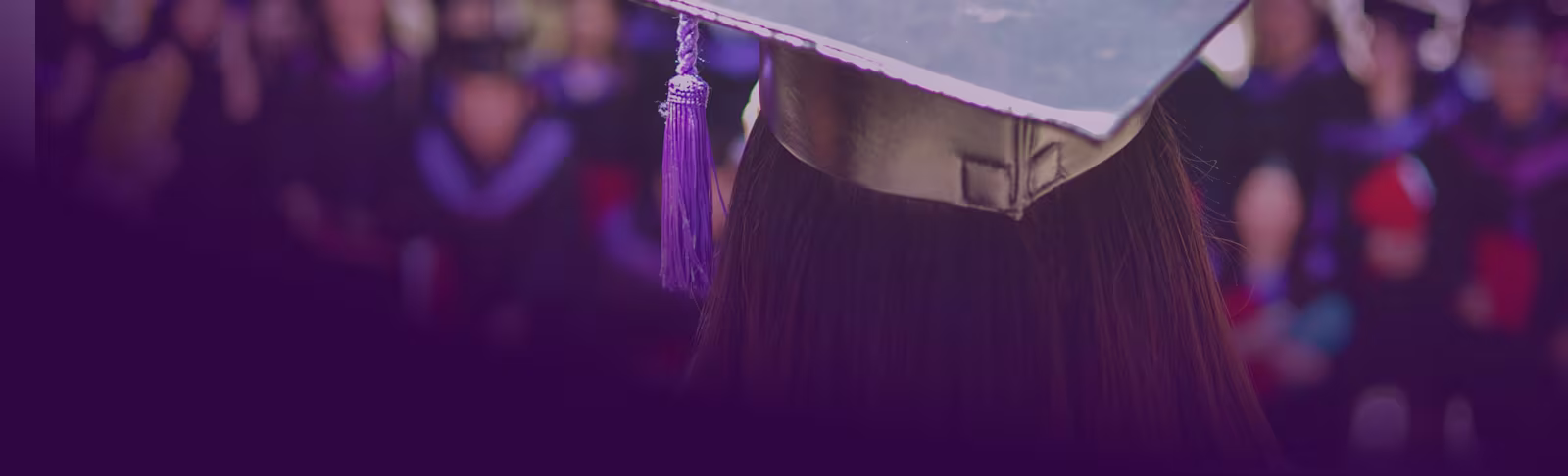An image of a woman with her graduation hat on, facing her fellow graduates
