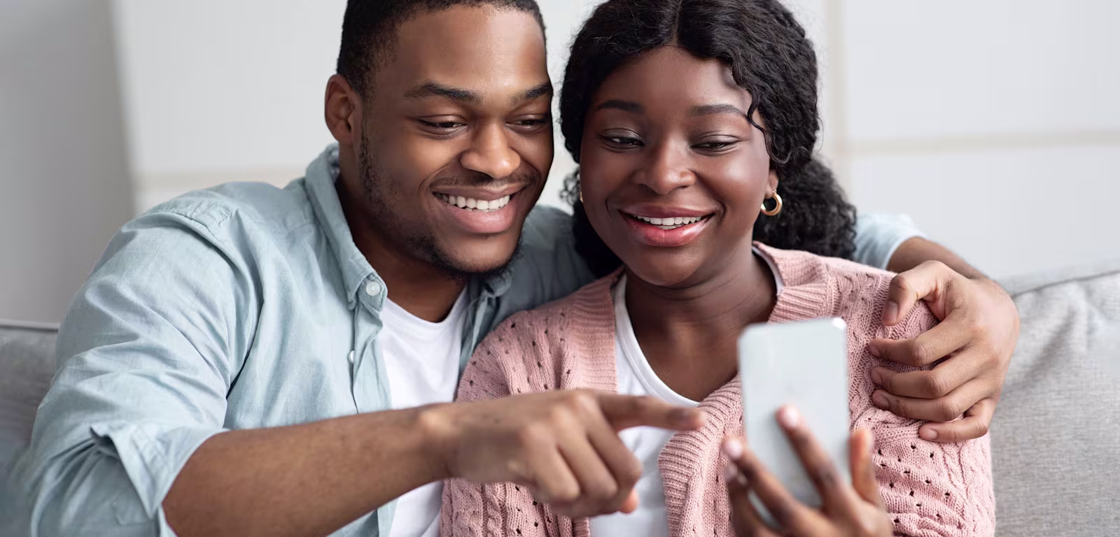 Help with sending money abroad A man sat on the sofa with his arms around a lady, both are looking at a phone