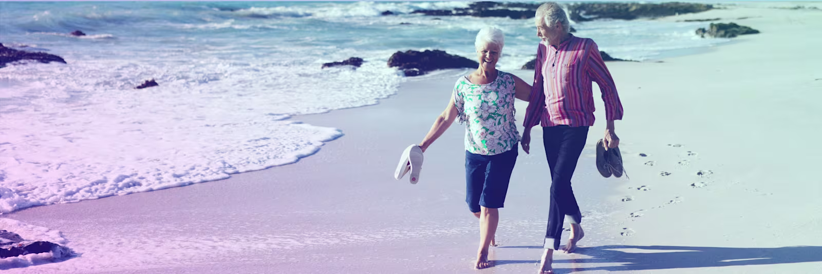 An image of an older couple walking on the beach