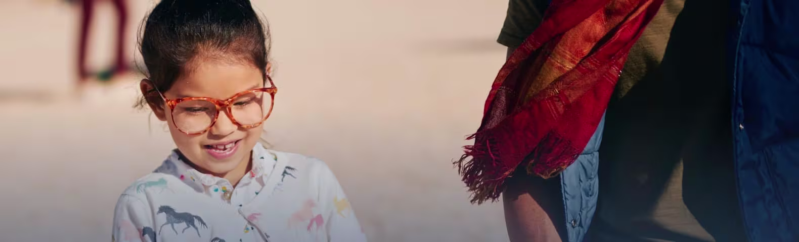 Little girl in large framed glasses looking down
