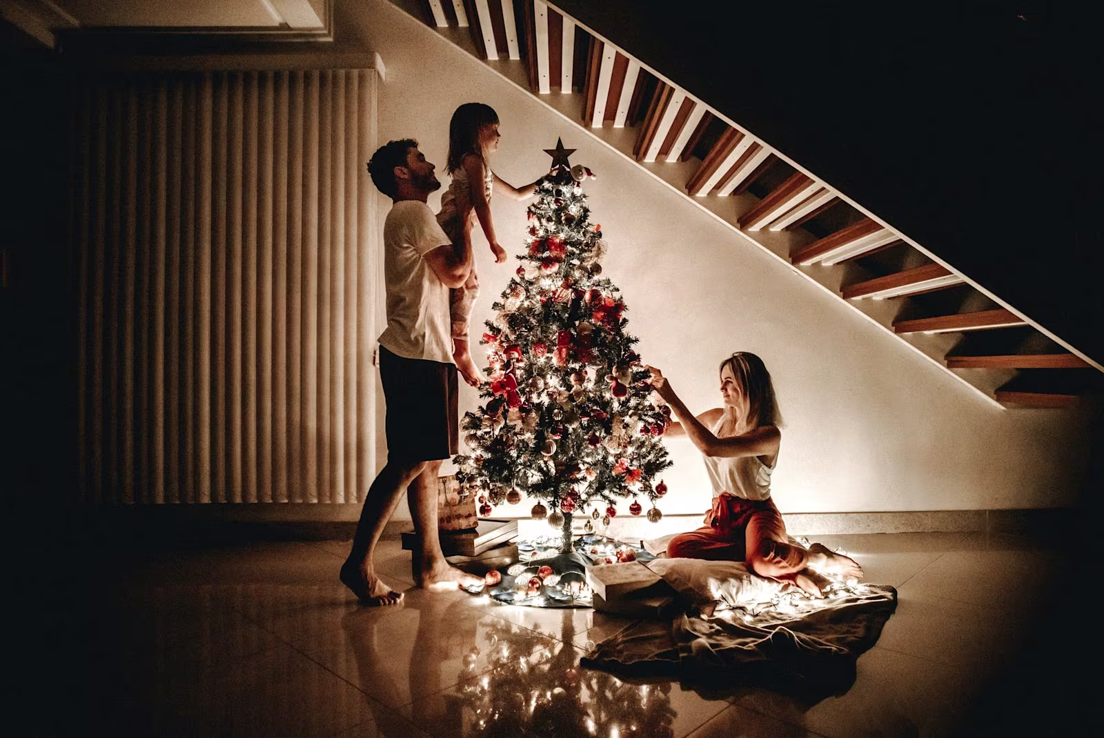 Madre, padre e hija colocando árbol de navidad