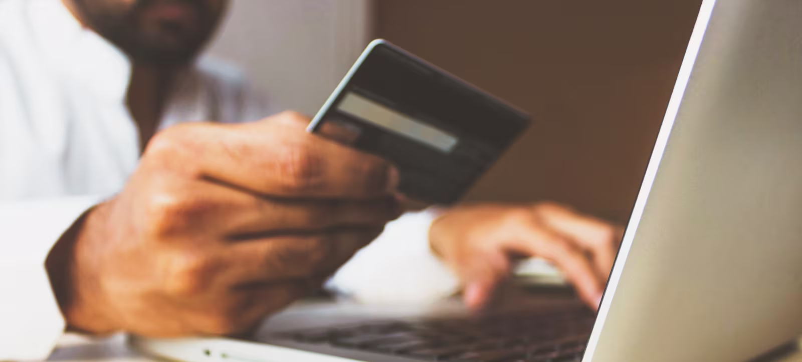 Swift codes A man using his laptop whilst looking at his bank card