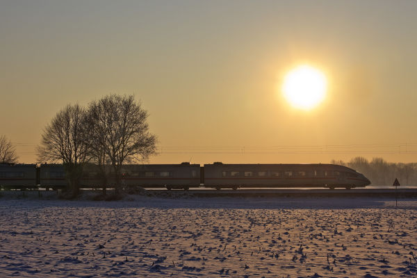 Copyright: Deutsche Bahn AG, Georg Wagner
Ein ICE fährt von links nach rechts durchs Bild, im Hintergrund geht die Sonne unter