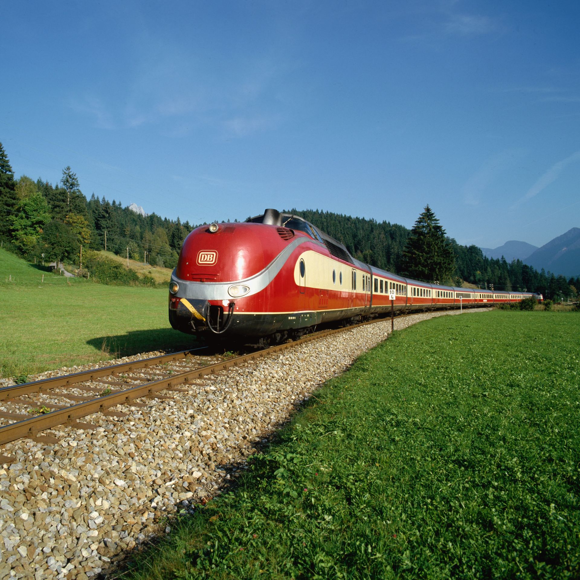 Das Bild zeigt einen alten Zug des TranseuropExpress in einer bergigen Landschaft.