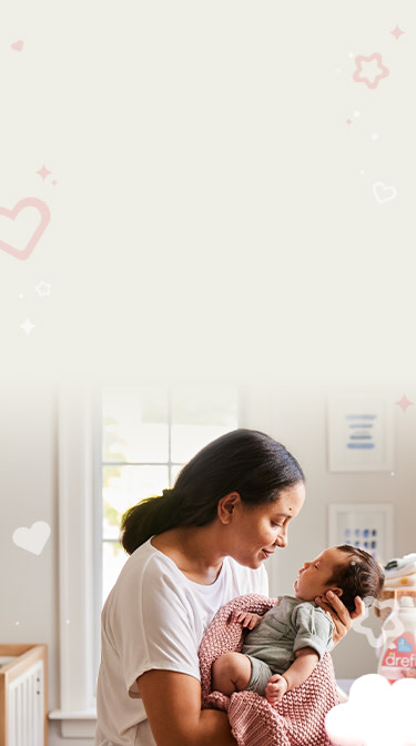 Mother gently holding her baby in pink blanket laundered with Dreft detergent for babies