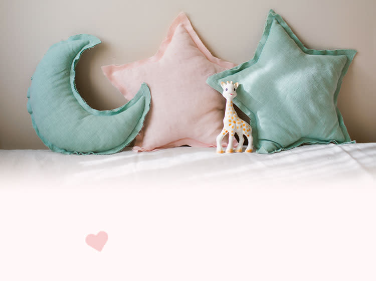 Two star-shaped pillows and one moon-shaped pillow lie on a bed
