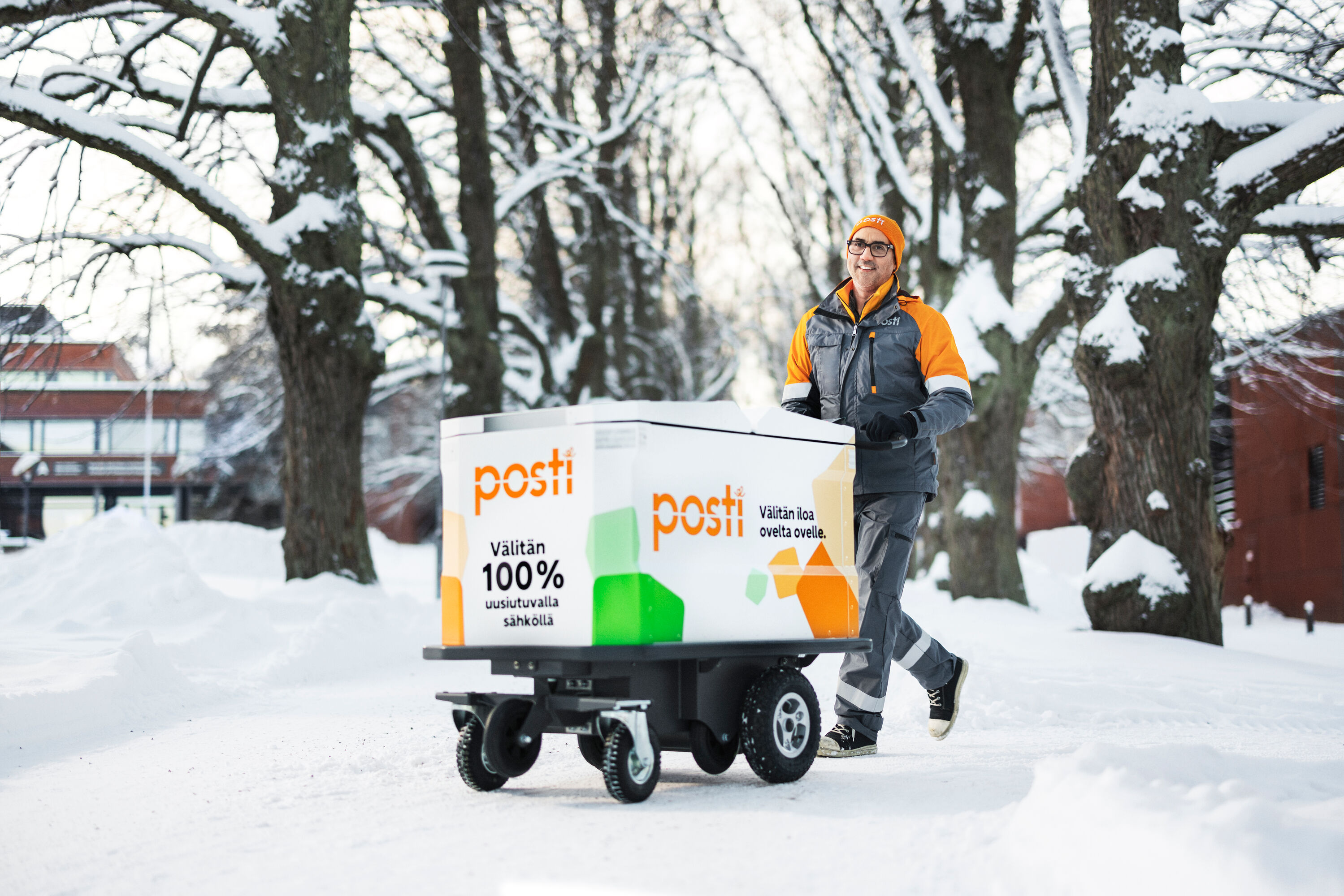 Post-worker is pushing a mail cart in a winter landscape