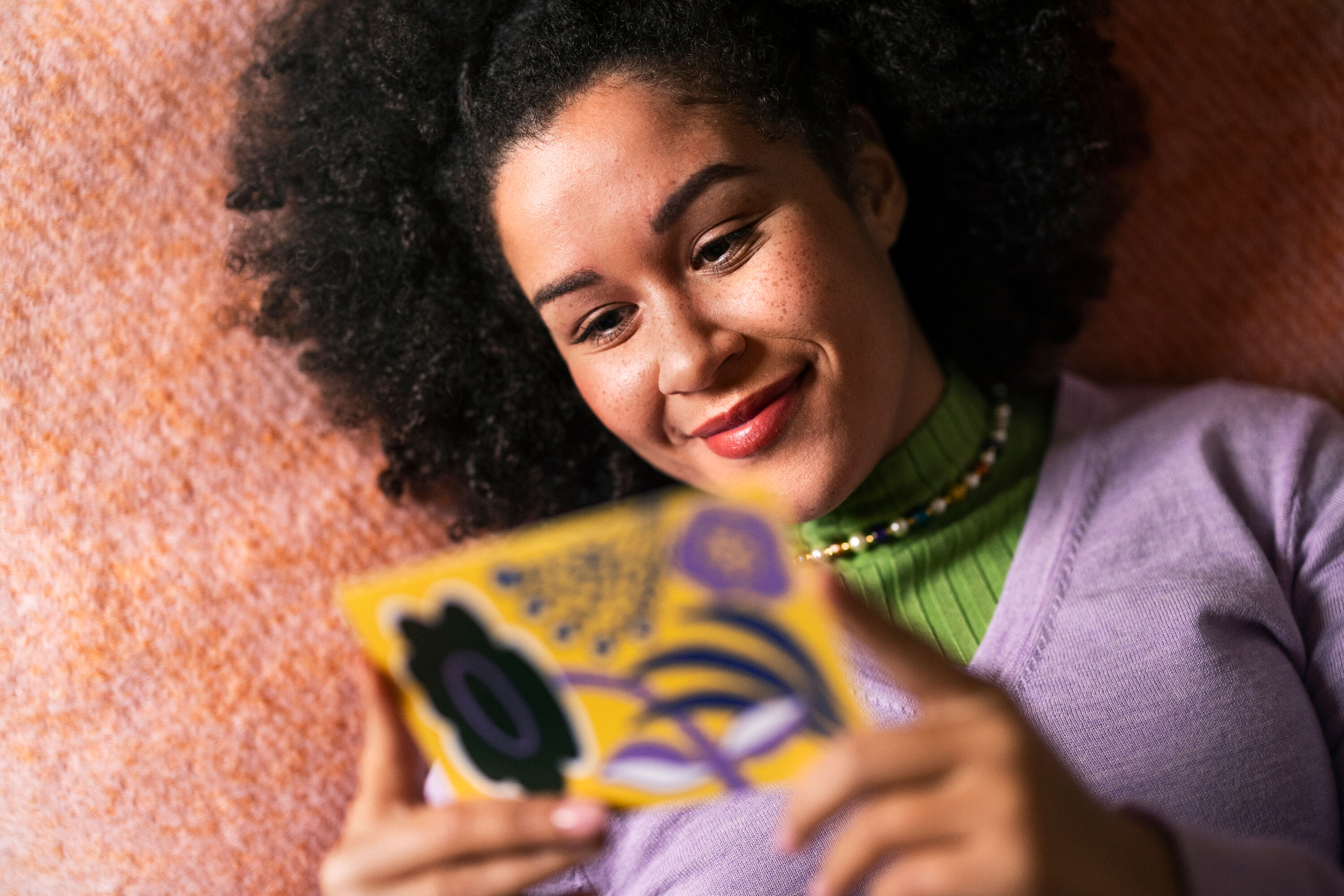 A woman reads a postcard with joy.