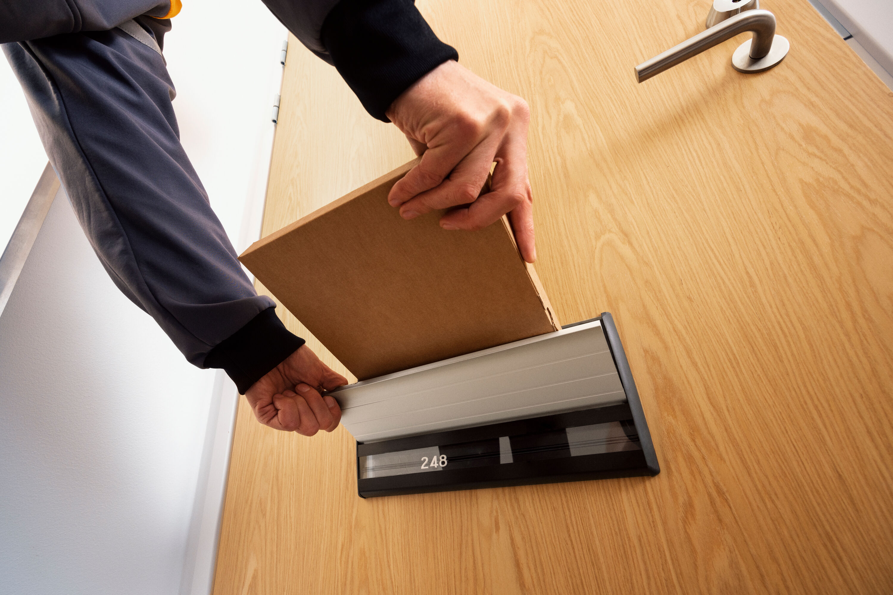 A postal worker putting a delivery through a mail slot. 