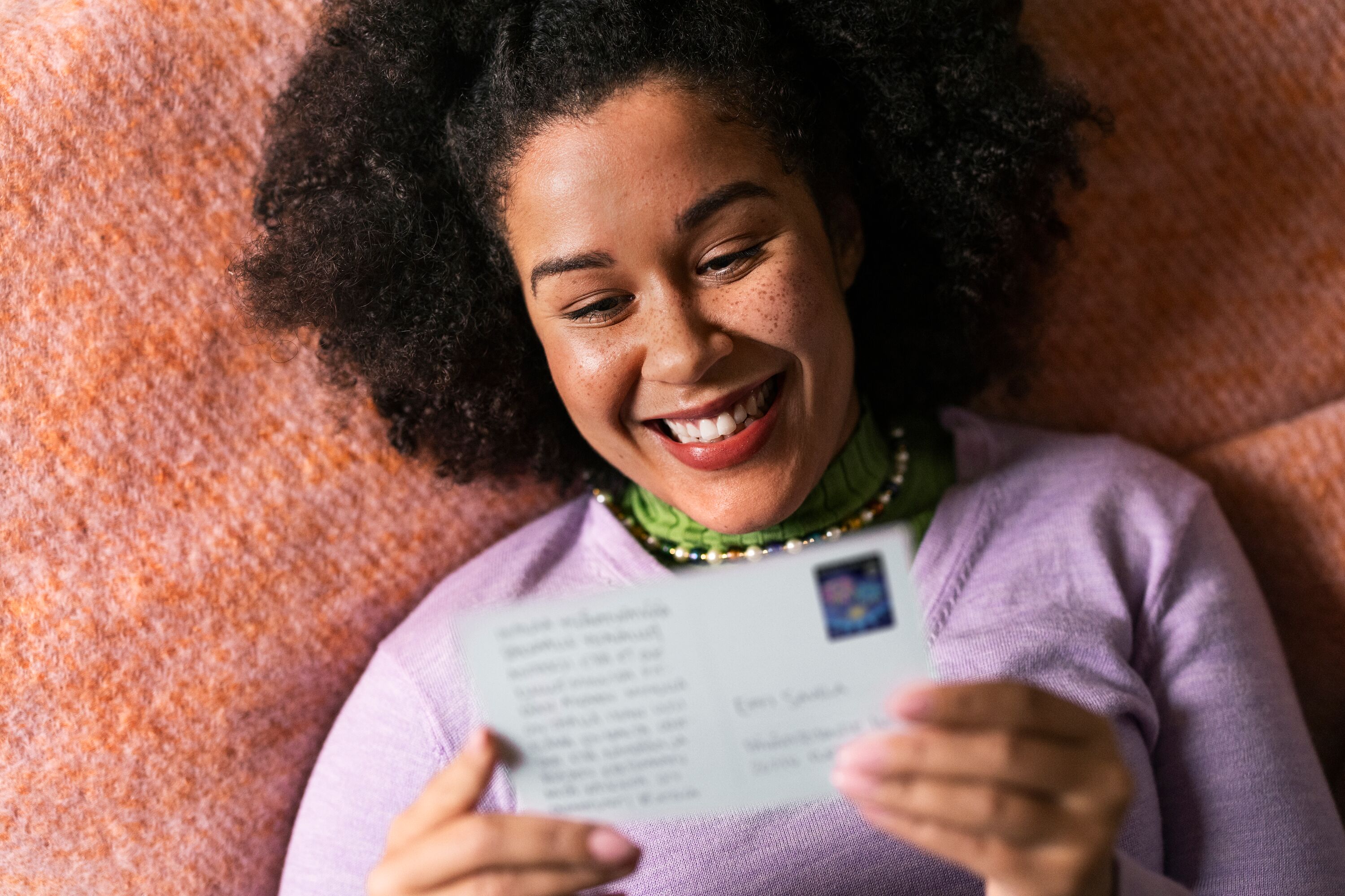 A happy woman is holding a postcard.