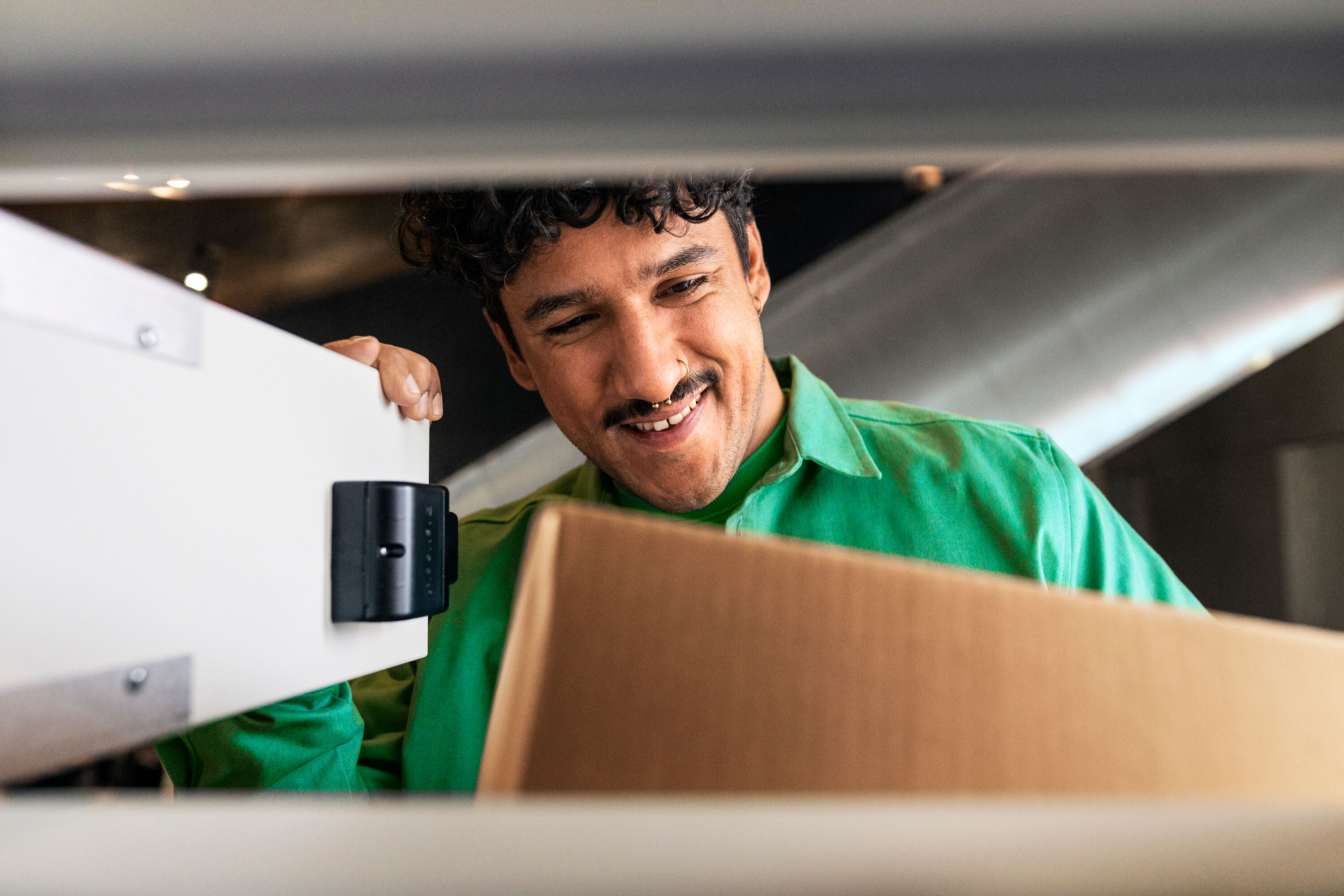 A smiling man picks up a package from the Posti Parcel Locker.