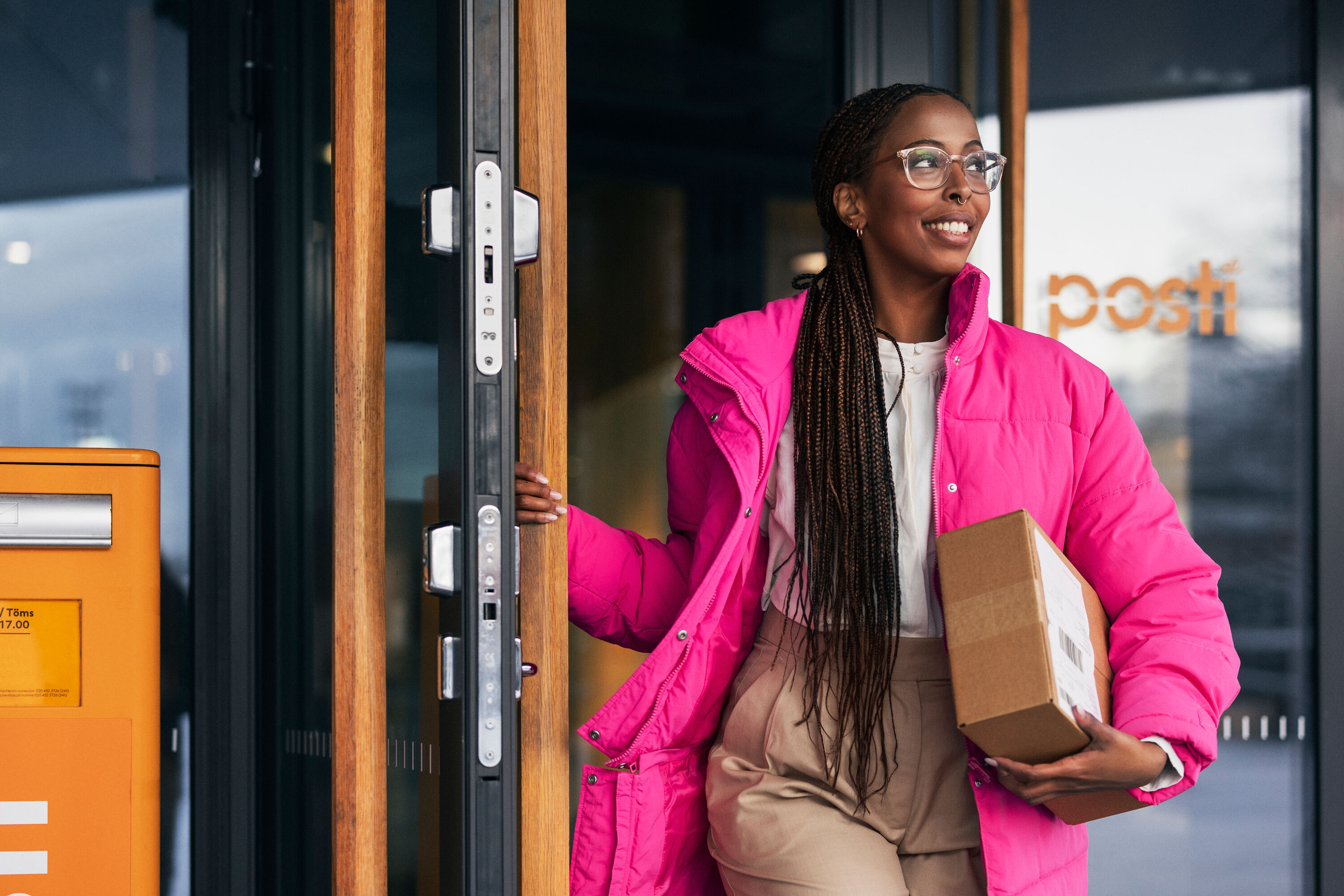 A woman in a pink coat is carrying a package.