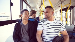 Father and teenage boy talking on a bus