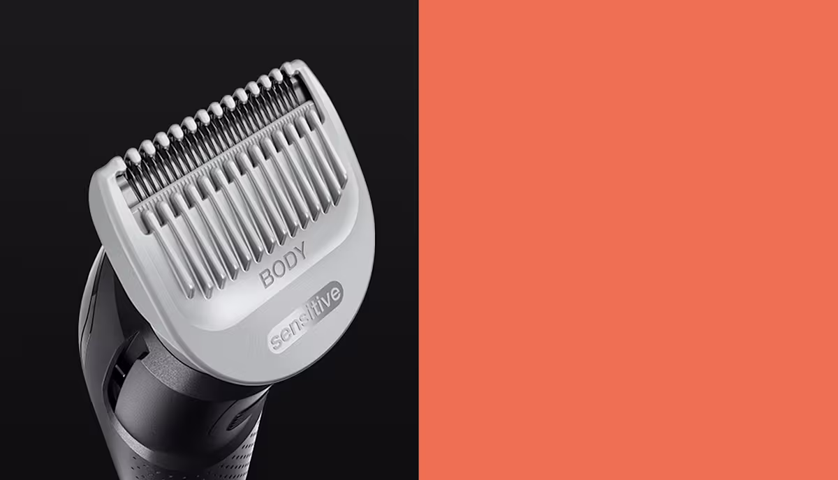 Close-up of a body hair trimmer with a sensitive comb attachment, featuring stainless steel blades on a dark background Close-up of a body hair trimmer with a sensitive comb attachment, featuring stainless steel blades on a dark background