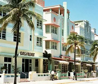 Miami street with art deco buildings and palm trees against a blue sky