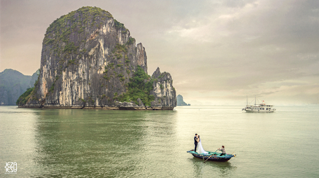 Bride and groom floating off in a small fishing boat in Ha Long Bay, Vietnam. Taken from a junk boat about 100 yards away.