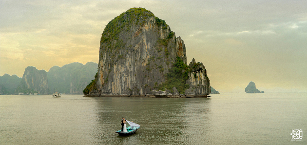 Bride and groom floating away in a fishing boat in Ha Long Bay, Vietnam. Taken from the vantage point of a junk boat, about 100 yards away.