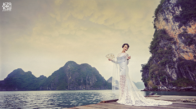 Bride with traditional asian hairstyling, wearing contemporary wedding gown. Standing on a dock in Ha Long Bay, Vietnam