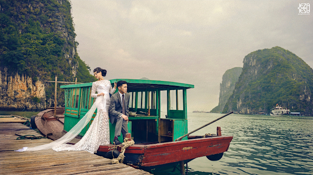 Bride and groom standing on a boat docked at one of the fishing villages in Ha Long Bay, Vietnam