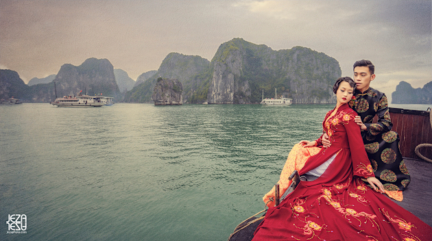 Bride and Groom in his and hers Áo dài, sitting at the edge of a junk boat in Ha Long Bay, Vietnam