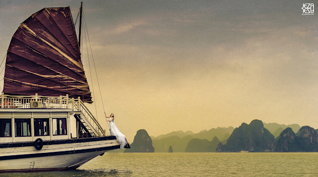 Bride in wedding gown, standing at the edge of a junk boat. Taken from a small fishing boat about 100 yards away.