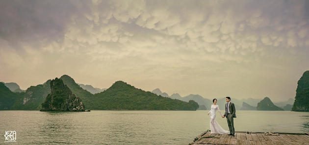 Bride and groom wearing traditional western wedding attire, standing on a dock in Ha Long Bay, Vietnam