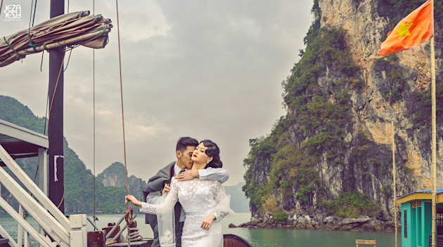 Bride and groom getting ready to board a junk boat docked at a fishing village in Ha Long Bay, Vietnam