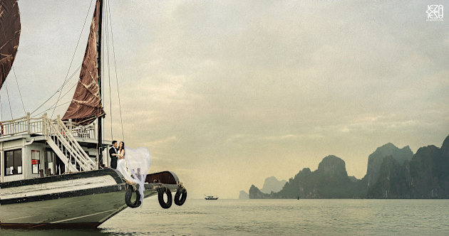 Bride and groom at the edge of a junk boat in Ha Long Bay, Vietnam. Taken from a small fishing boat about 100 yards away.