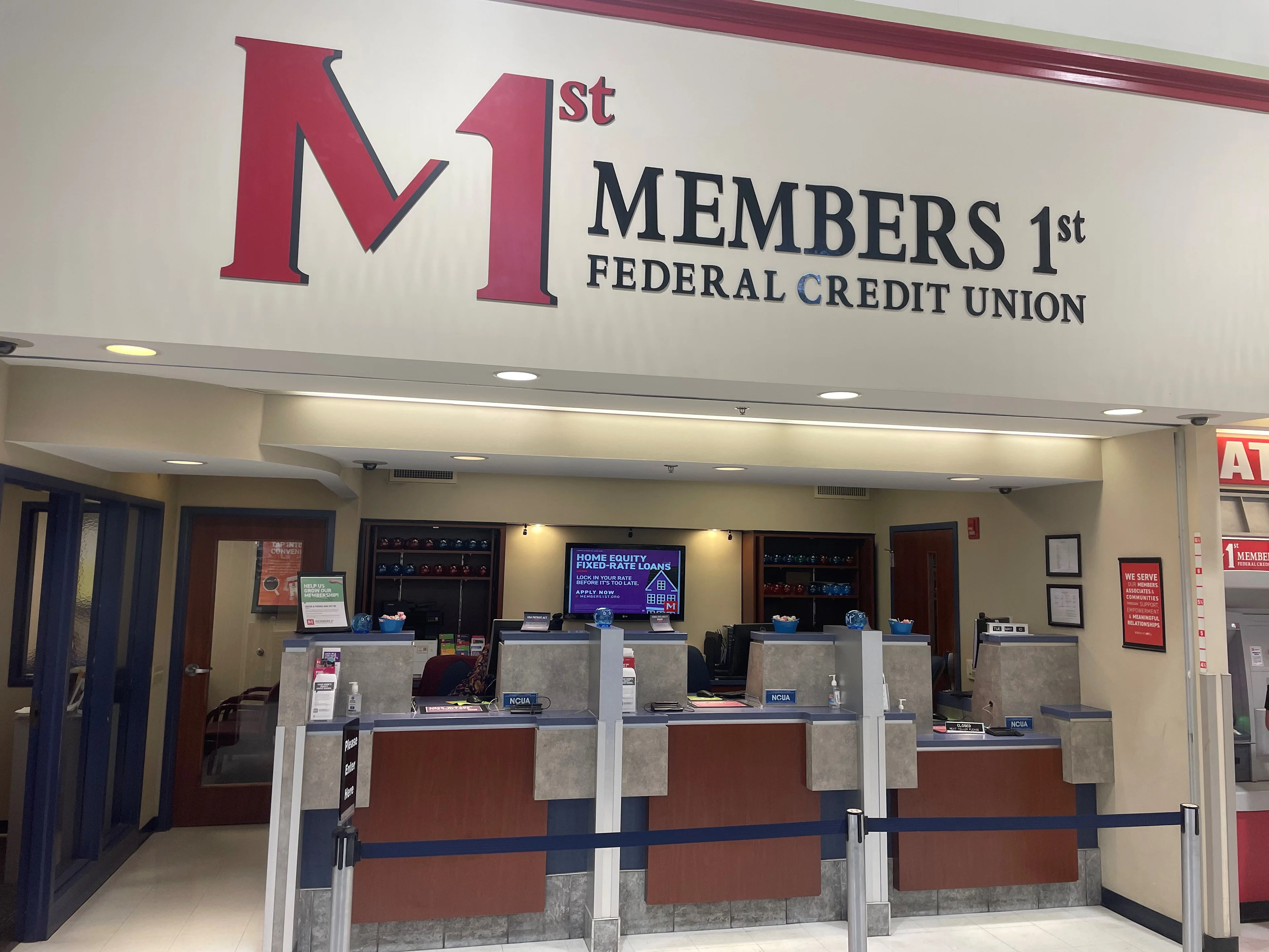 Manchester Giant Members 1st Federal Credit Union branch interior with teller stations and large red and blue logo sign on white wall.