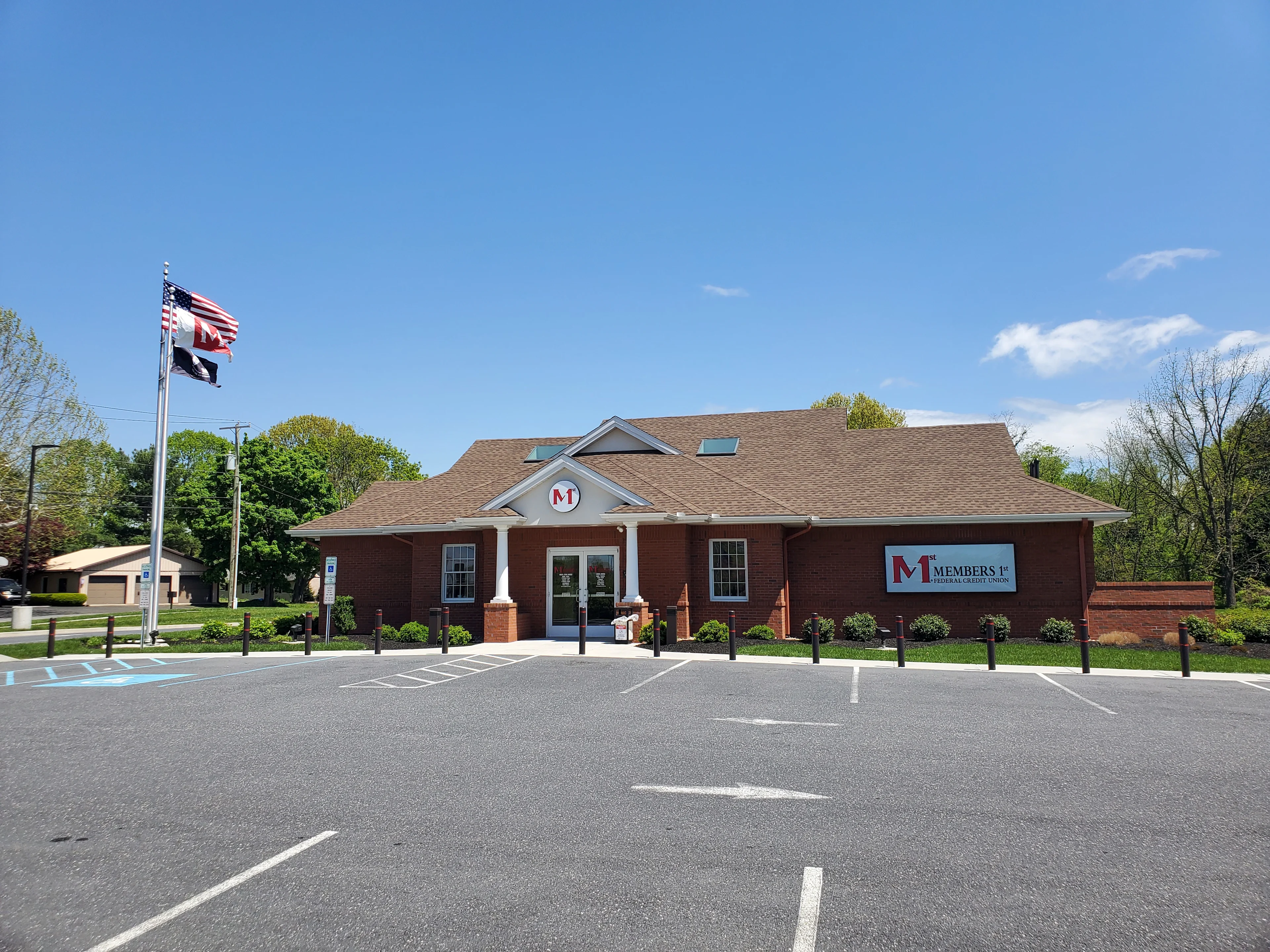 Halifax Members 1st Federal Credit Union building with white columns, flags, and parking lot under blue sky.