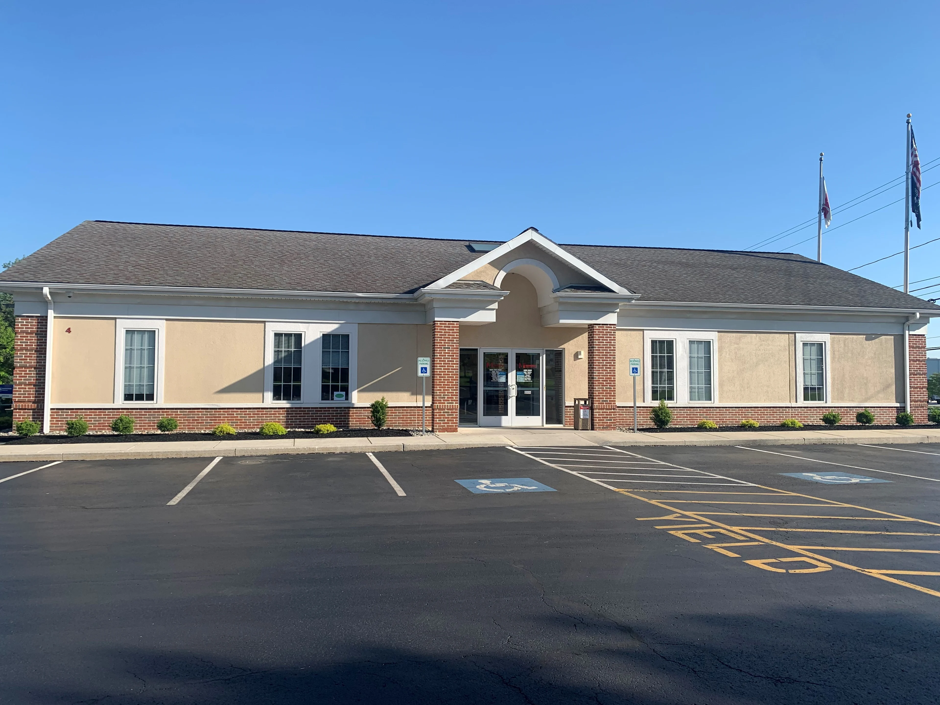 Market Plaza Members 1st Federal Credit Union branch with beige stucco, brick accents, arched entrance, and parking lot with handicap spaces.