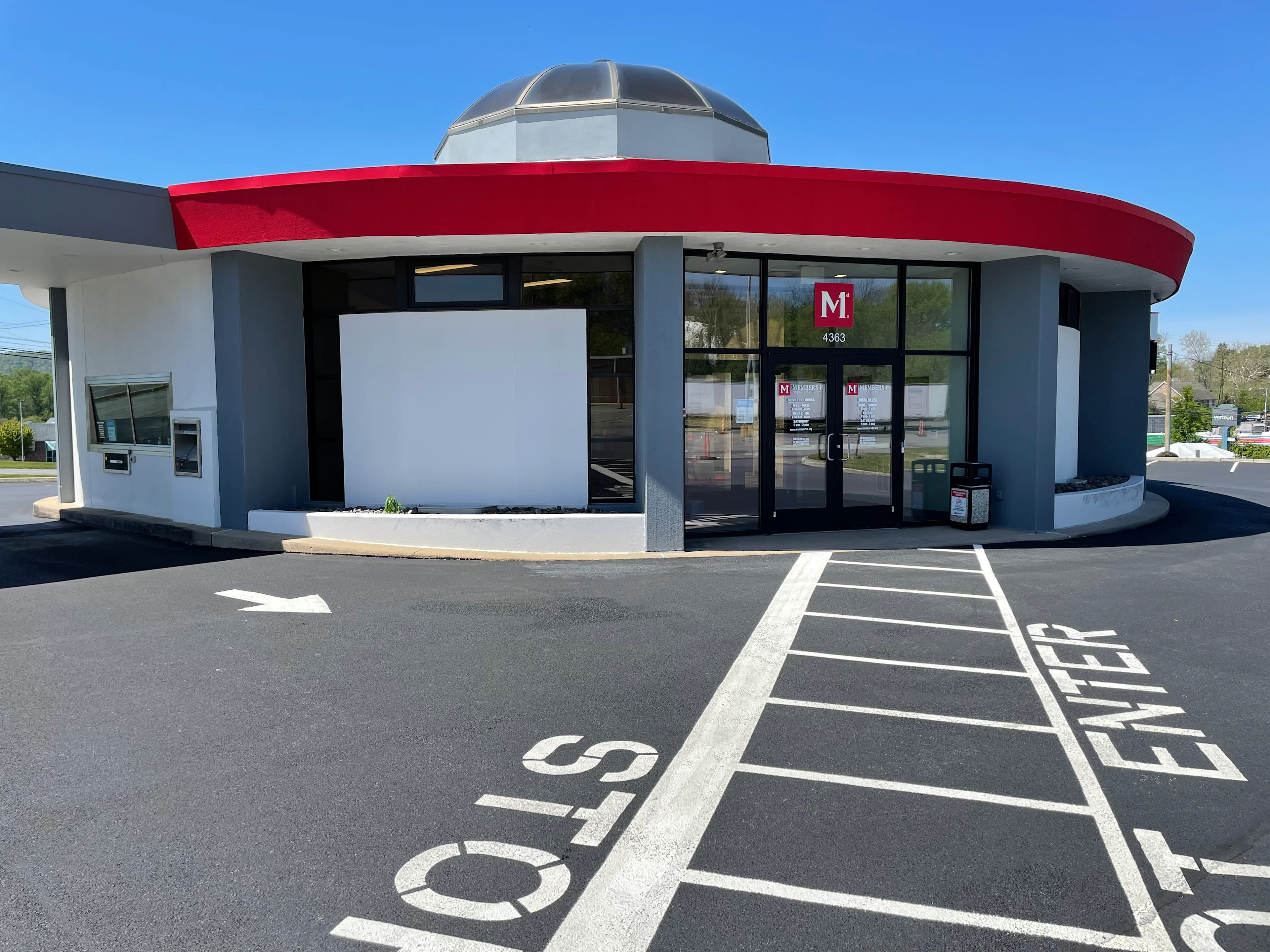 Exeter Members 1st Federal Credit Union modern building with red curved awning, gray dome, glass entrance doors, and drive-thru lanes under blue sky.