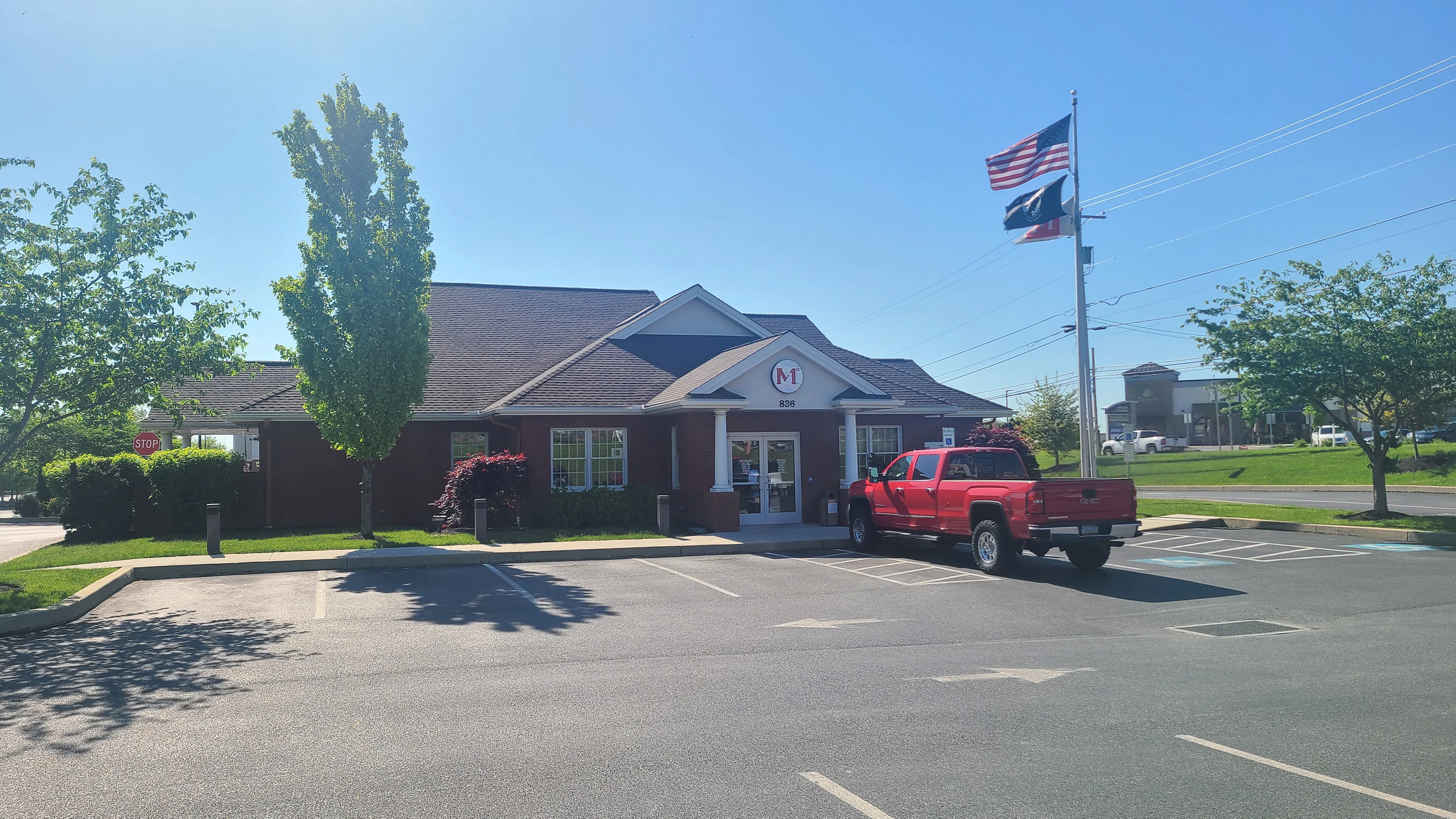 Ephrata Members 1st Federal Credit Union building with white columns and red pickup truck parked in front under American and Texas flags.