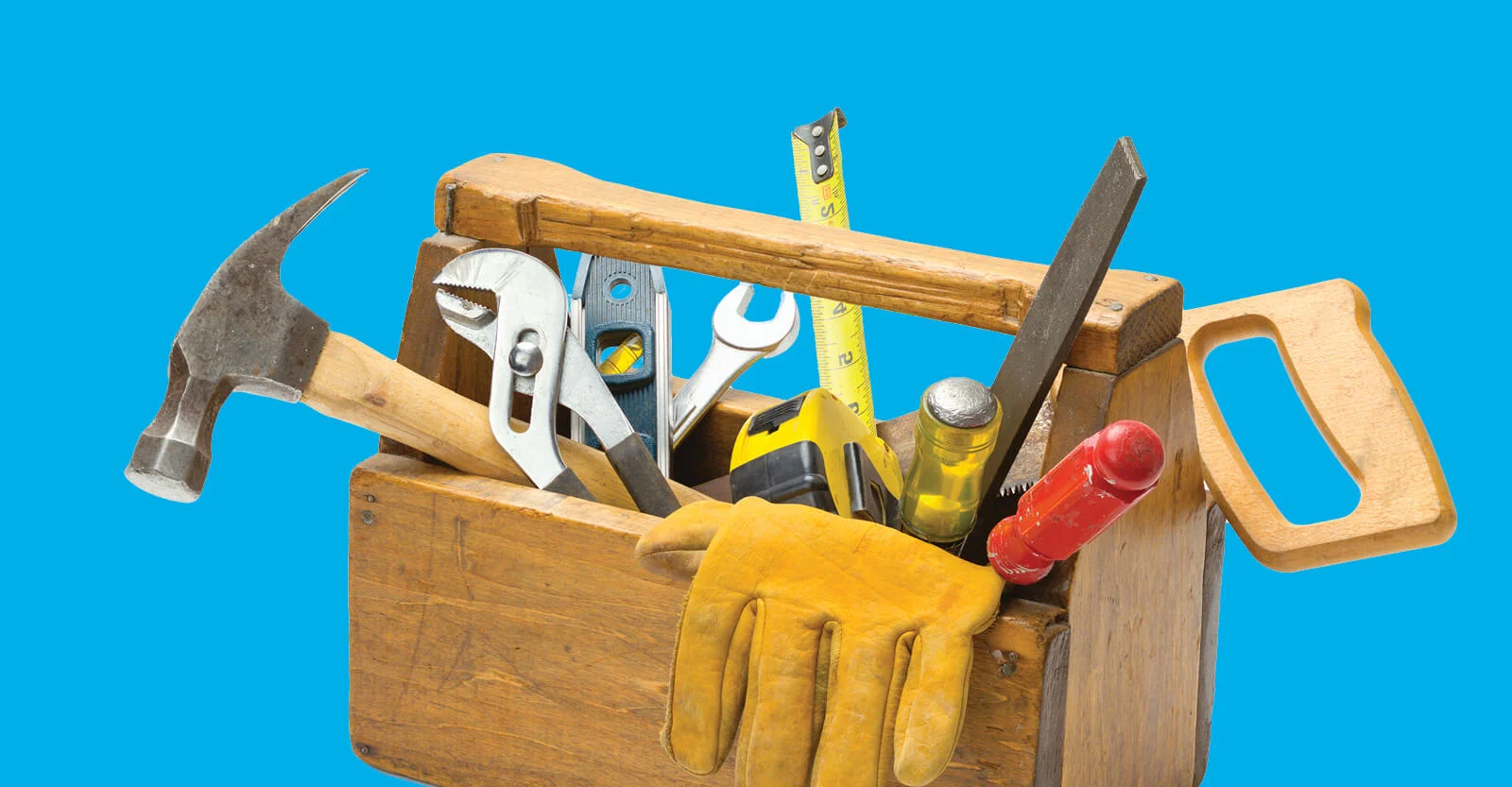 Wooden toolbox filled with various hand tools including hammer, wrenches, saw, tape measure, and yellow work gloves on blue background.