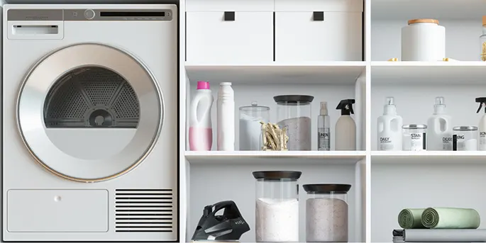 White dryer next to organized shelving unit with laundry supplies, detergents, and storage containers in modern laundry room.