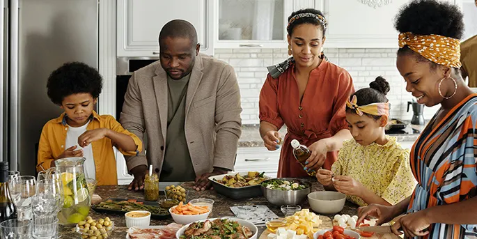 Multi-generational family cooking together in a bright modern kitchen, preparing a meal with fresh ingredients.