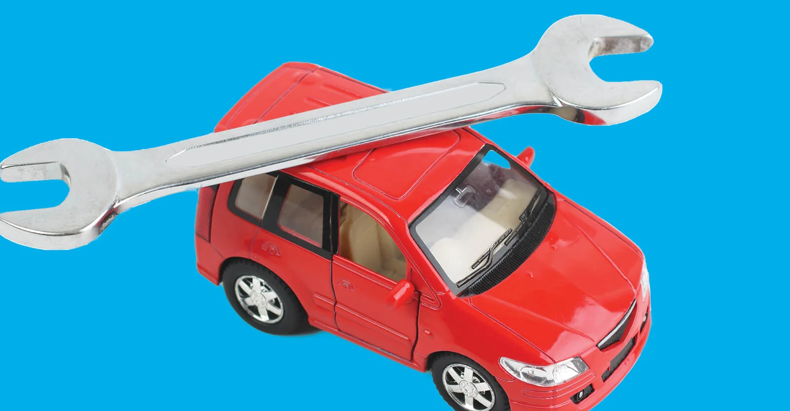 Red toy car with chrome wrench resting on top against bright blue background, representing auto repair or maintenance.