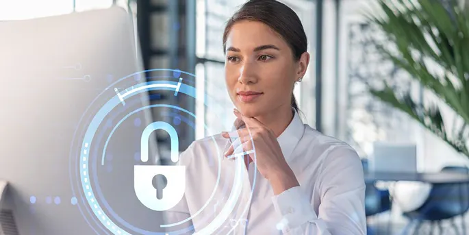 Professional woman in white shirt with hand on chin, viewing holographic blue padlock security icon in modern office