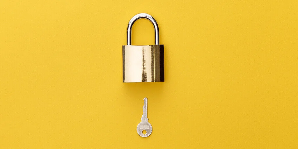 Silver padlock with chrome shackle and matching key displayed separately on bright yellow background.