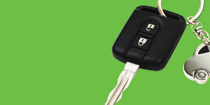 Black car key fob with two buttons and silver keychain on bright green background