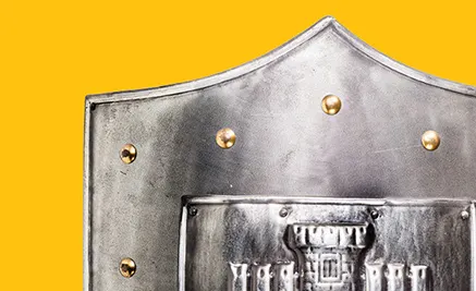 Medieval knight's helmet in silver metal with gold rivets against a bright yellow background