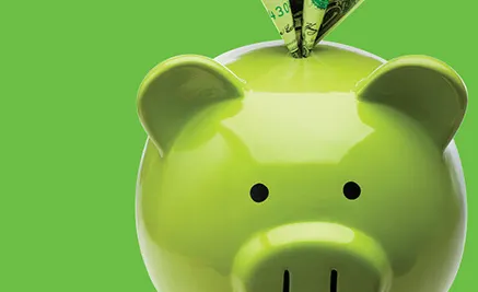 Green piggy bank with dollar bill being inserted against bright green background