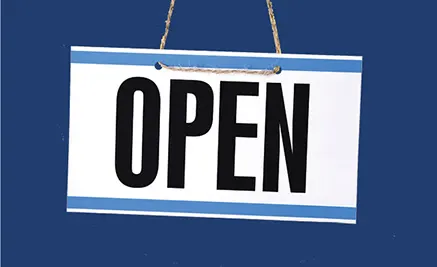 White rectangular sign with bold black text reading OPEN, hanging by rope against a dark blue background.