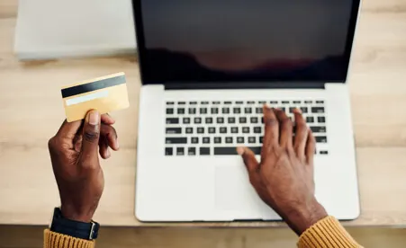 Hands using credit card at laptop