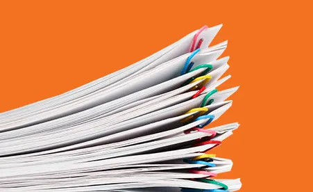Stack of paperclipped papers on orange background