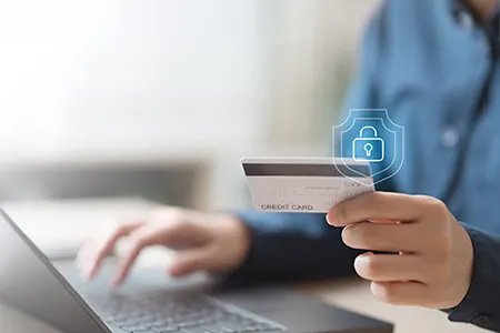 Person using laptop with credit card and lock shield overlay