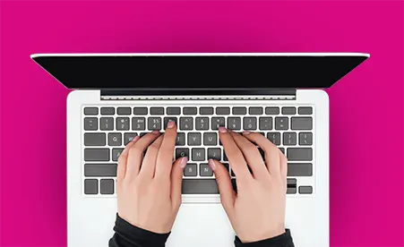 Hands on laptop keyboard on pink background