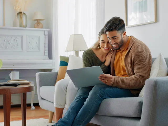 Couple sitting on couch looking at laptop computer