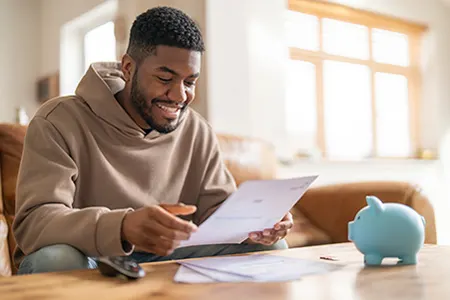 Man smiling at bill with piggy bank