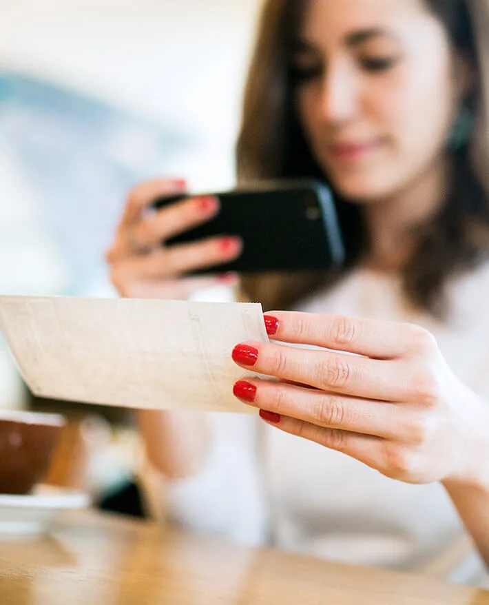 Woman with red nail polish holding credit card and smartphone for online shopping or payment transaction